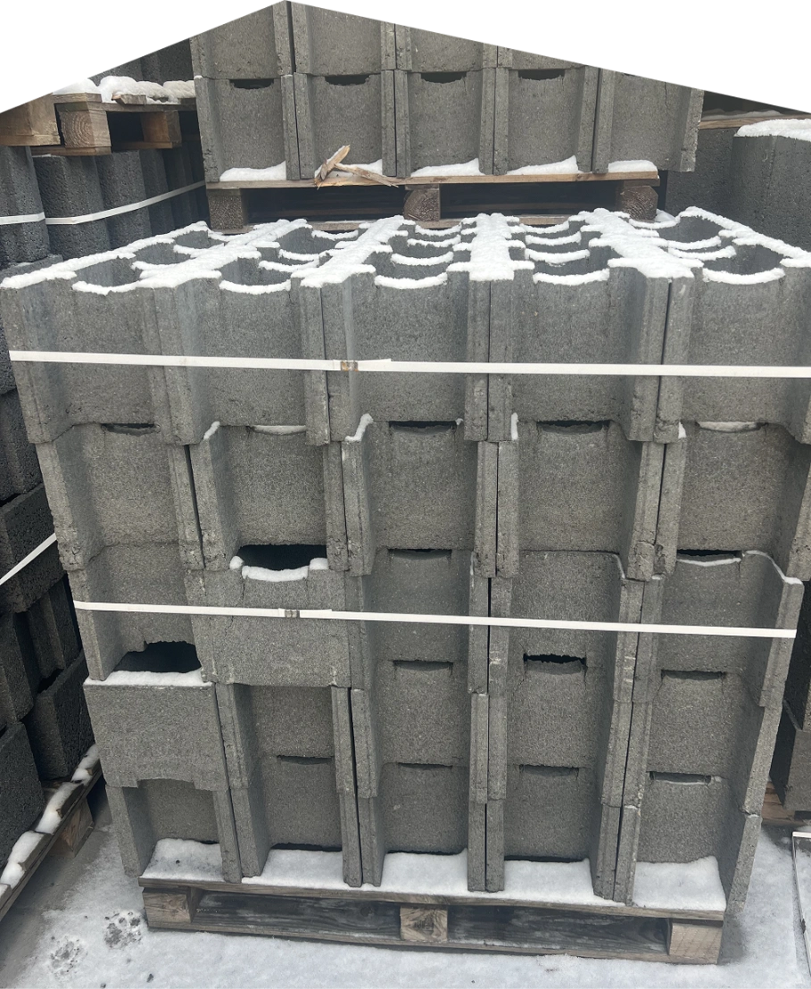 Stos bloczków betonowych na palecie z widocznym śniegiem